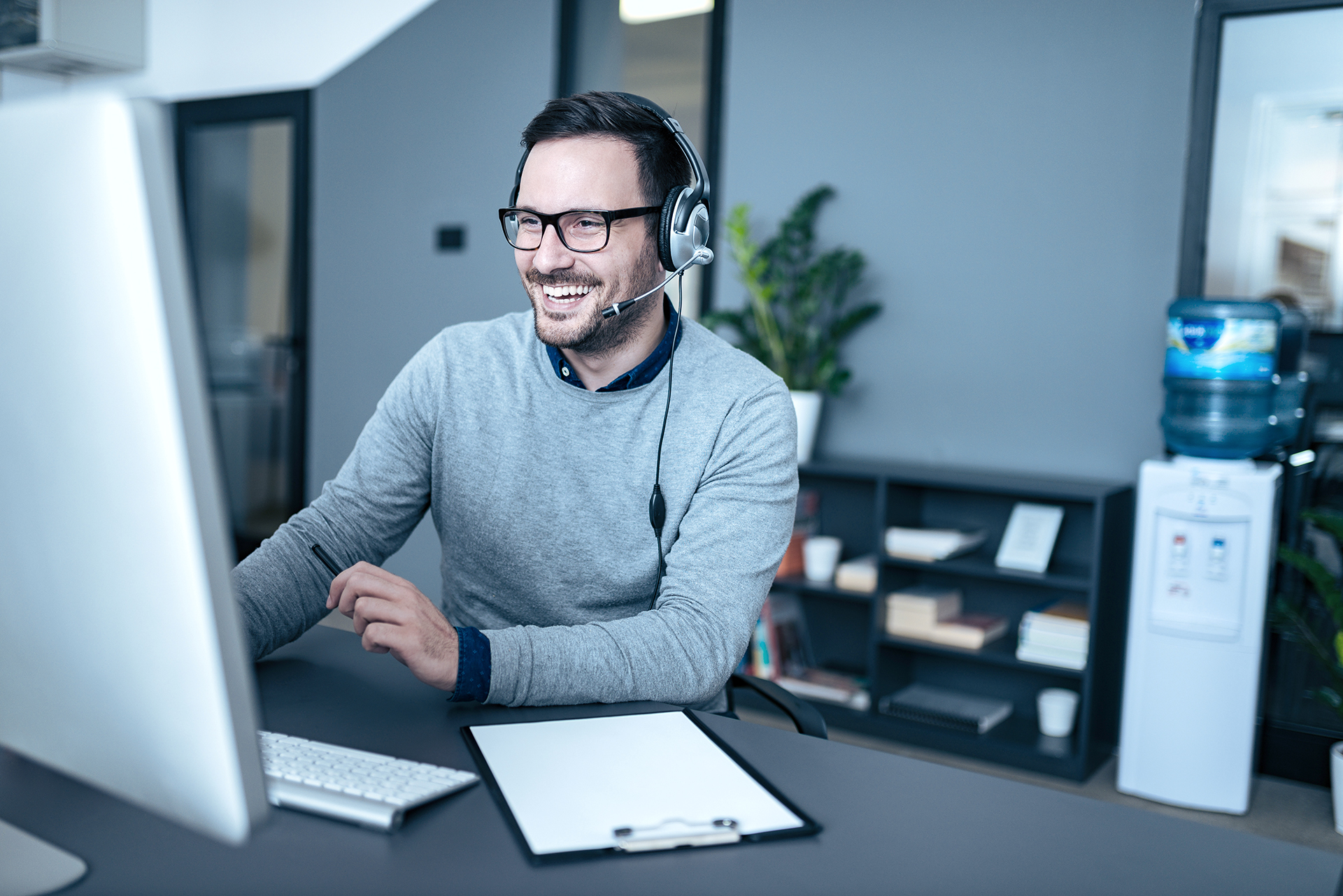 Portrait of a handsome smiling man with headset working on the computer.
